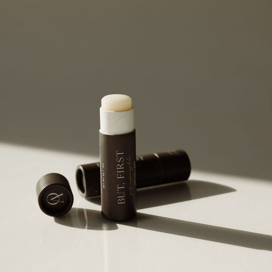 Makeup stick with white cap and brown body on a light surface with a neutral background