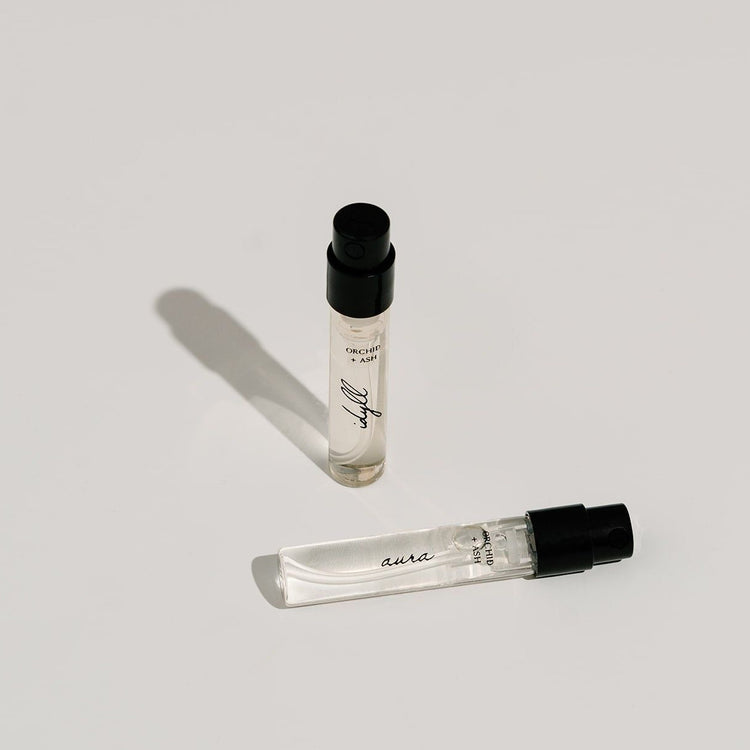 Two small perfume bottles with black caps on a light gray background