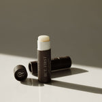 Makeup stick with white cap and brown body on a light surface with a neutral background