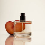 Perfume bottle with a peach slice on a light background