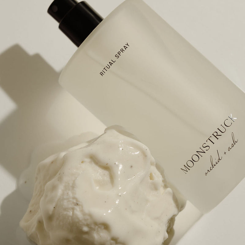 Bottle of MoonsTruck ritual spray with a bath bomb on a neutral background