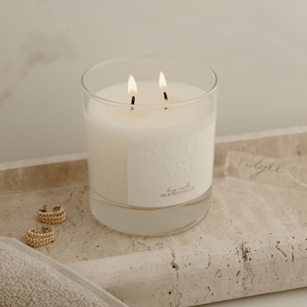 Candle in a glass holder on a textured surface with a neutral background