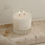 Candle in a glass holder on a textured surface with a neutral background