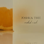 Candle with 'Joshua Tree' branding on a reflective surface