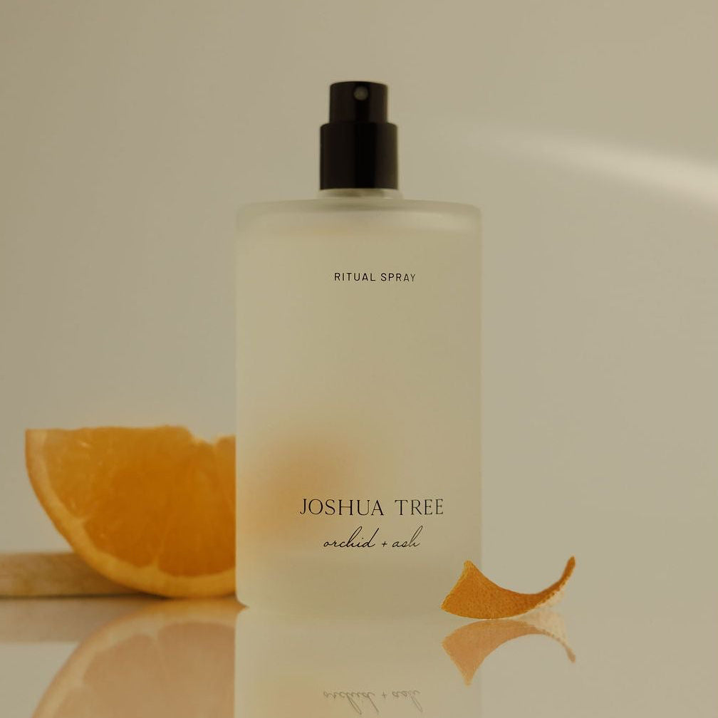 Bottle of Joshua Tree product with an orange slice on a reflective surface