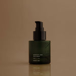 Green skincare serum bottle with black pump on a brown background