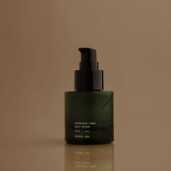 Green skincare serum bottle with black pump on a brown background