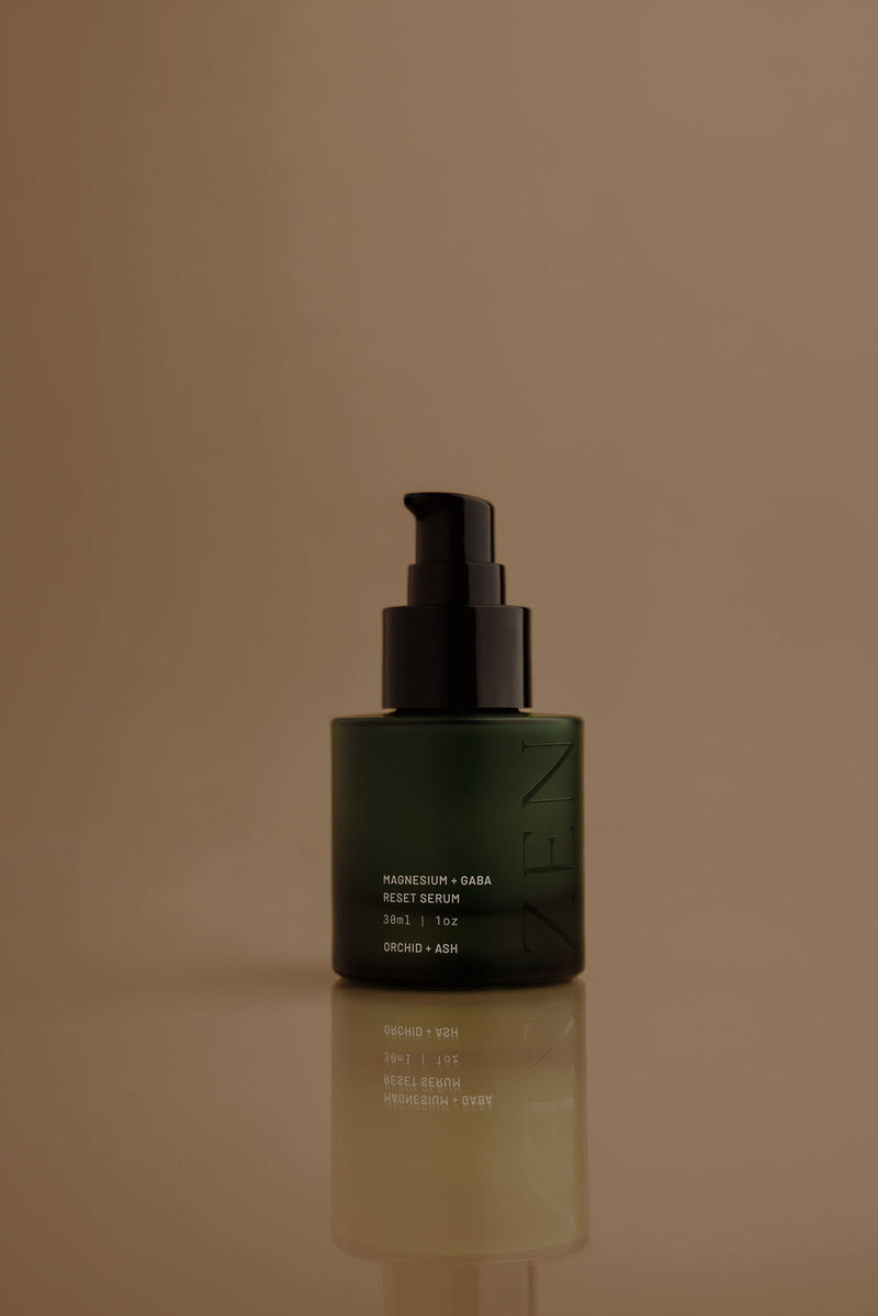 Green skincare serum bottle with black pump on a brown background