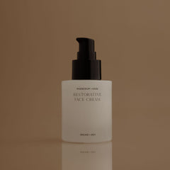White face cream bottle with black pump on a brown background