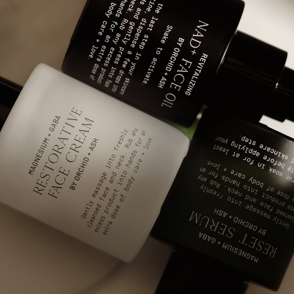 Skincare products including a face cream, serum, and oil on a neutral background