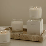 Three lit candles on a decorative tray with a neutral background