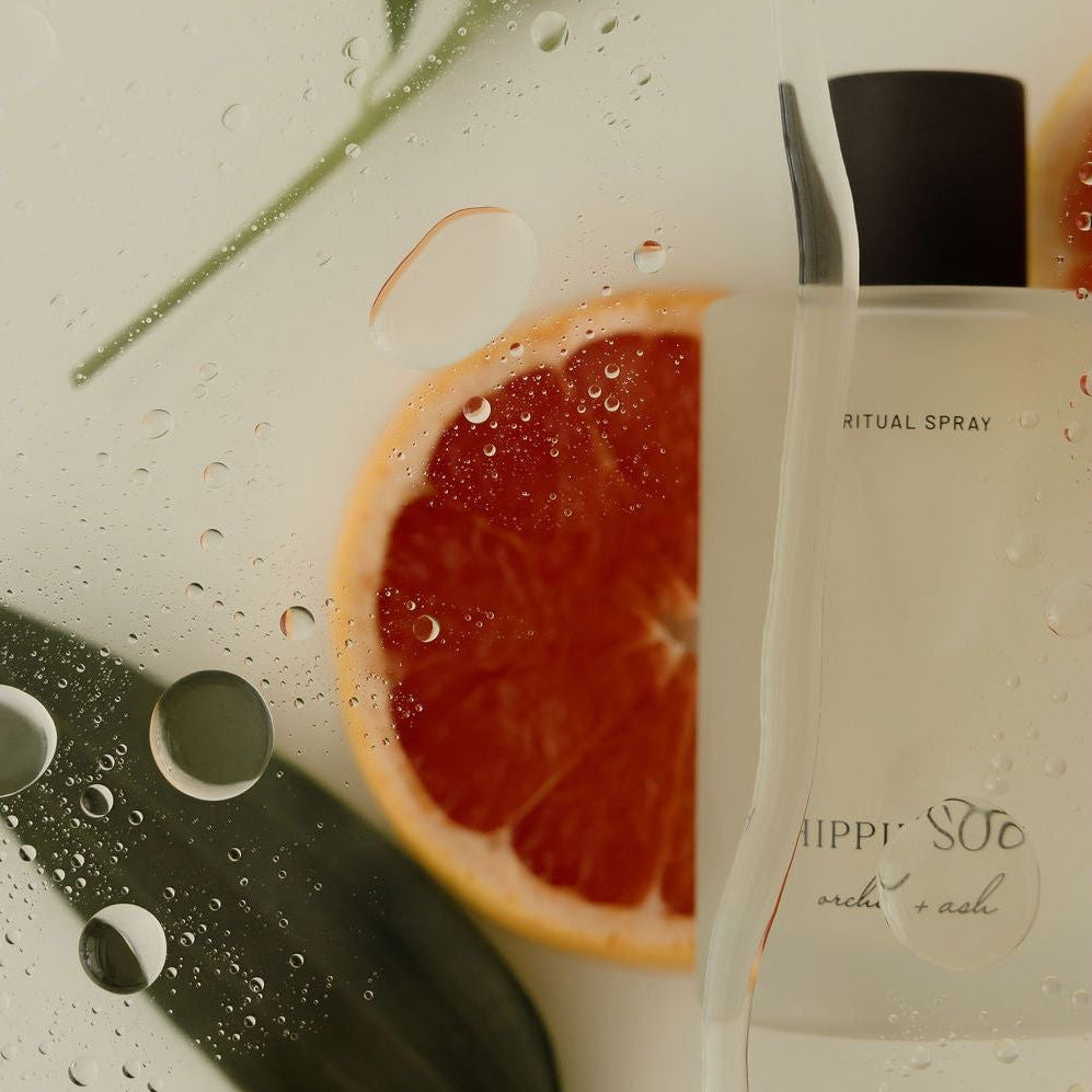 Spray bottle labeled 'Mimmi & Co' with a half-sliced grapefruit and leaves on a white background