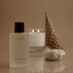Bottle of 'Moonstruck' with a waffle cone and candle on a reflective surface.