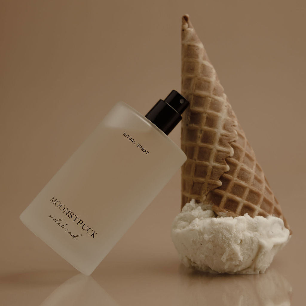 Perfume bottle with waffle cone and coral on a reflective surface