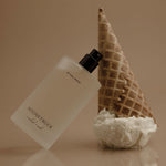 Perfume bottle with waffle cone and coral on a reflective surface