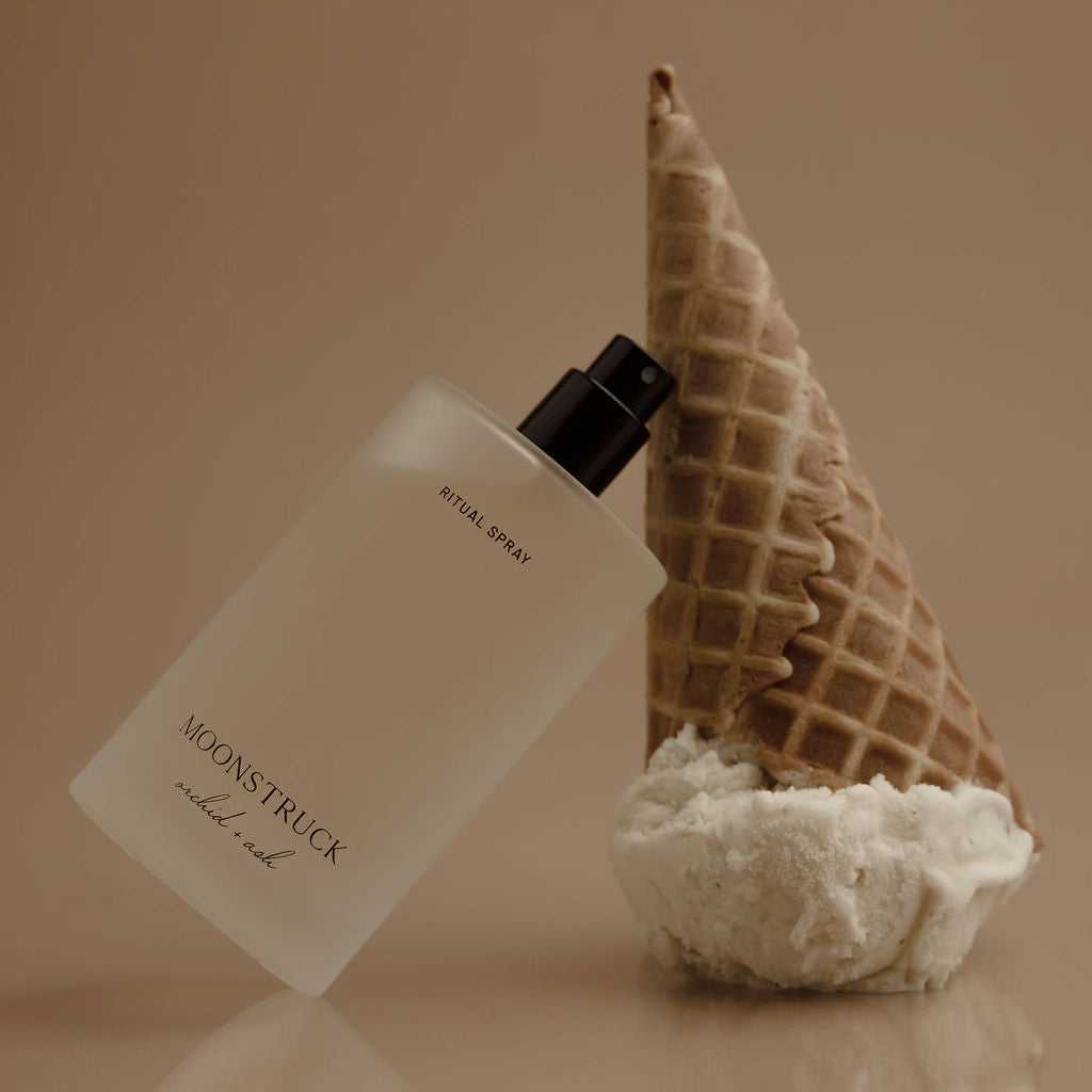 Perfume bottle with waffle cone and coral on a reflective surface