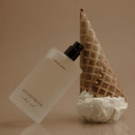 Perfume bottle with waffle cone and coral on a reflective surface
