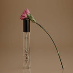 Perfume bottle with a pink flower on a brown background