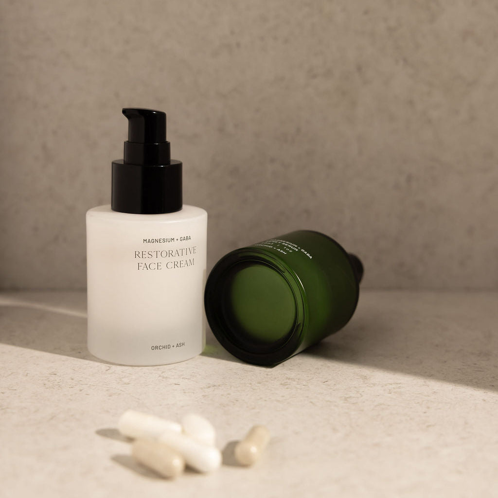 Two skincare products on a textured surface with a neutral background