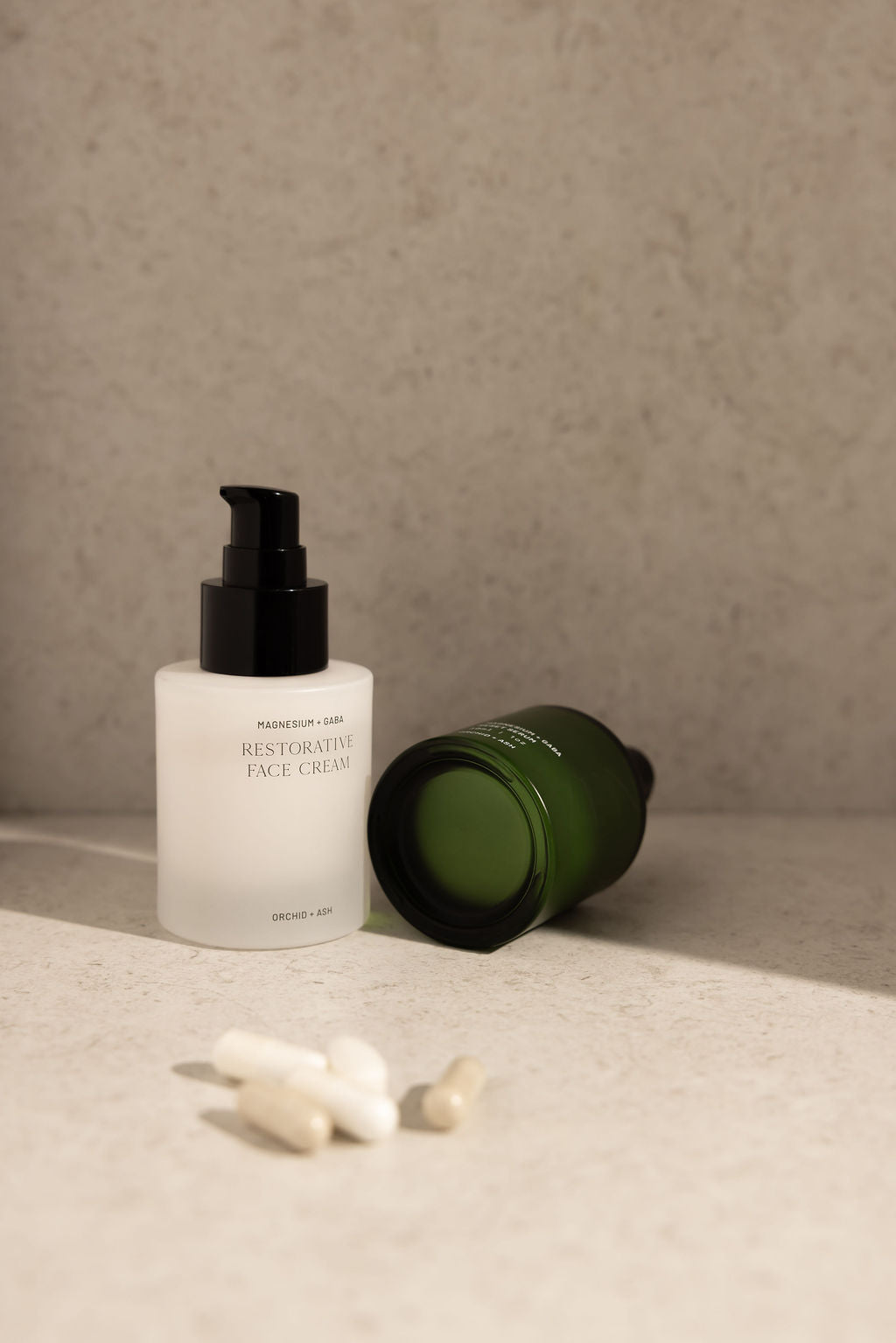 Two skincare products on a textured surface with a neutral background