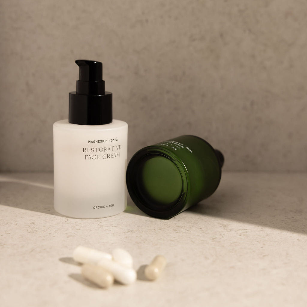 Two skincare products on a textured surface with a neutral background