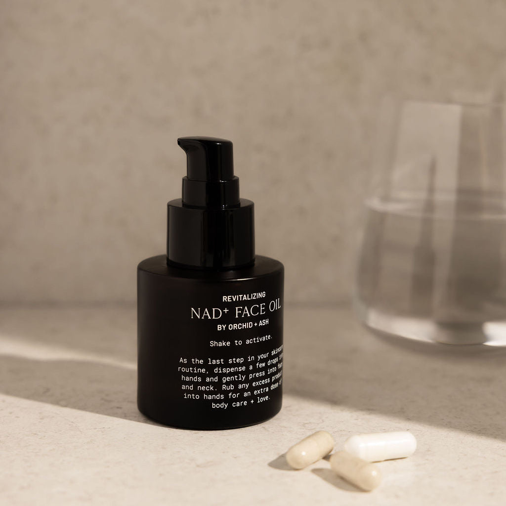 Black facial oil bottle with pump on a neutral surface
