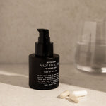Black facial oil bottle with pump on a neutral surface