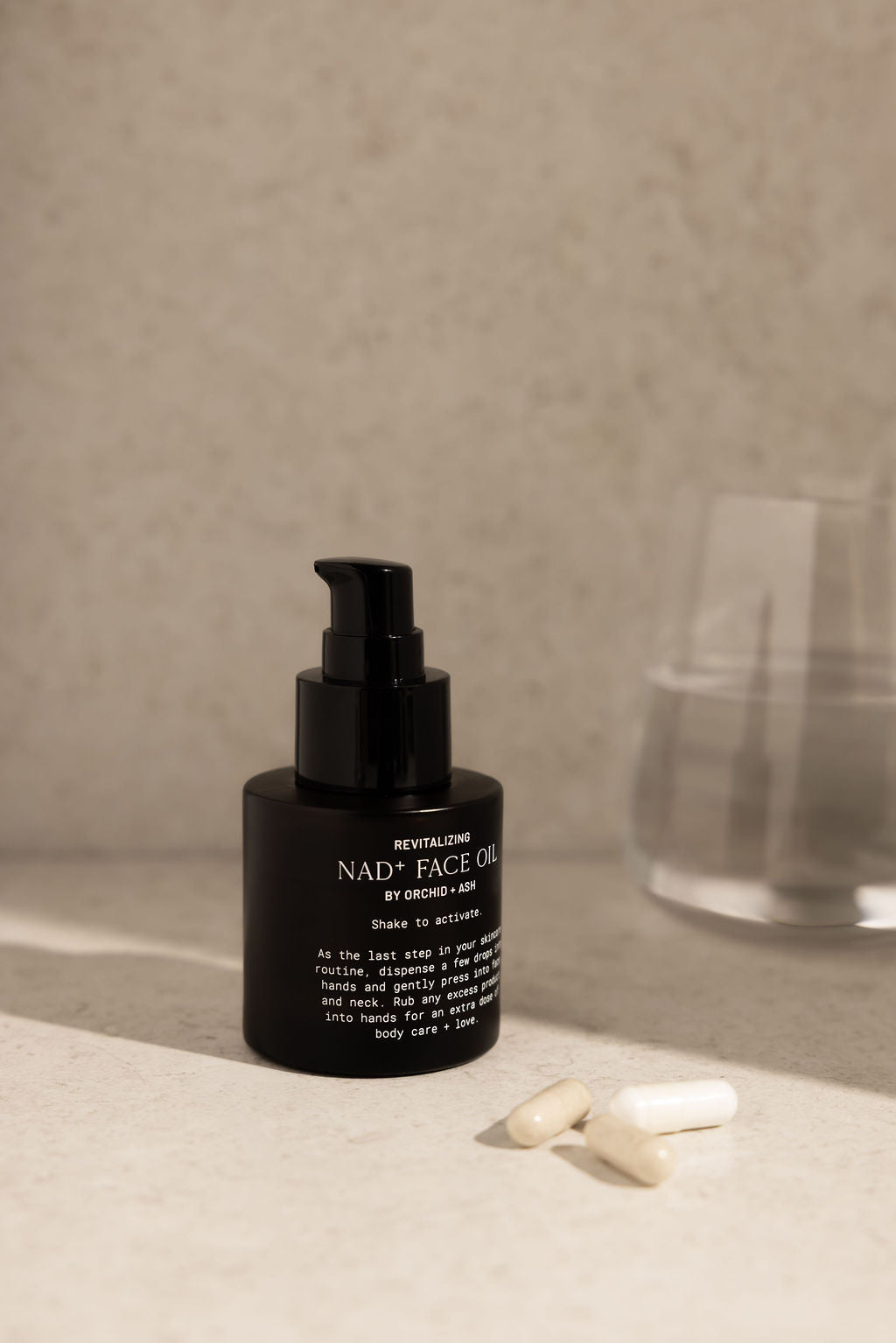 Black facial oil bottle with pump on a neutral surface