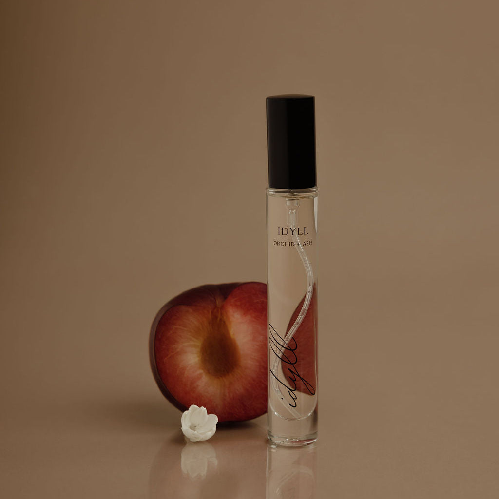 Perfume bottle with plum and flower on a brown background