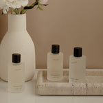 Set of skincare products on a tray with a vase of flowers on a neutral background