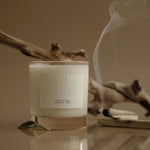 Candle with 'Truffle Ash' label on a reflective surface with a blurred background