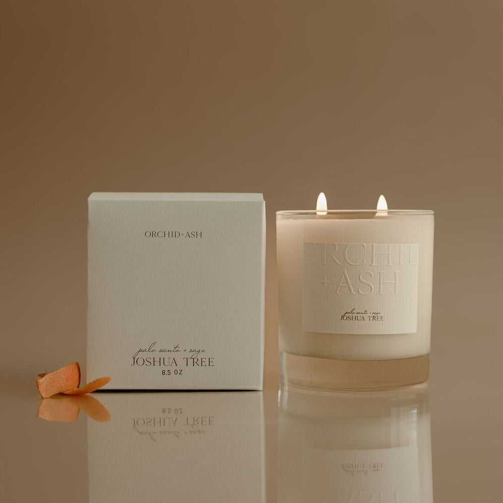 Candle and packaging with 'Joshua Tree' branding on a reflective surface.