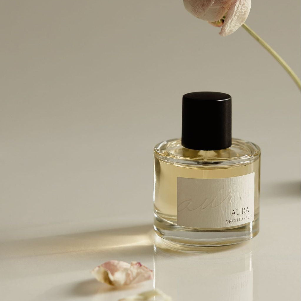 Perfume bottle with a dried flower on a neutral background
