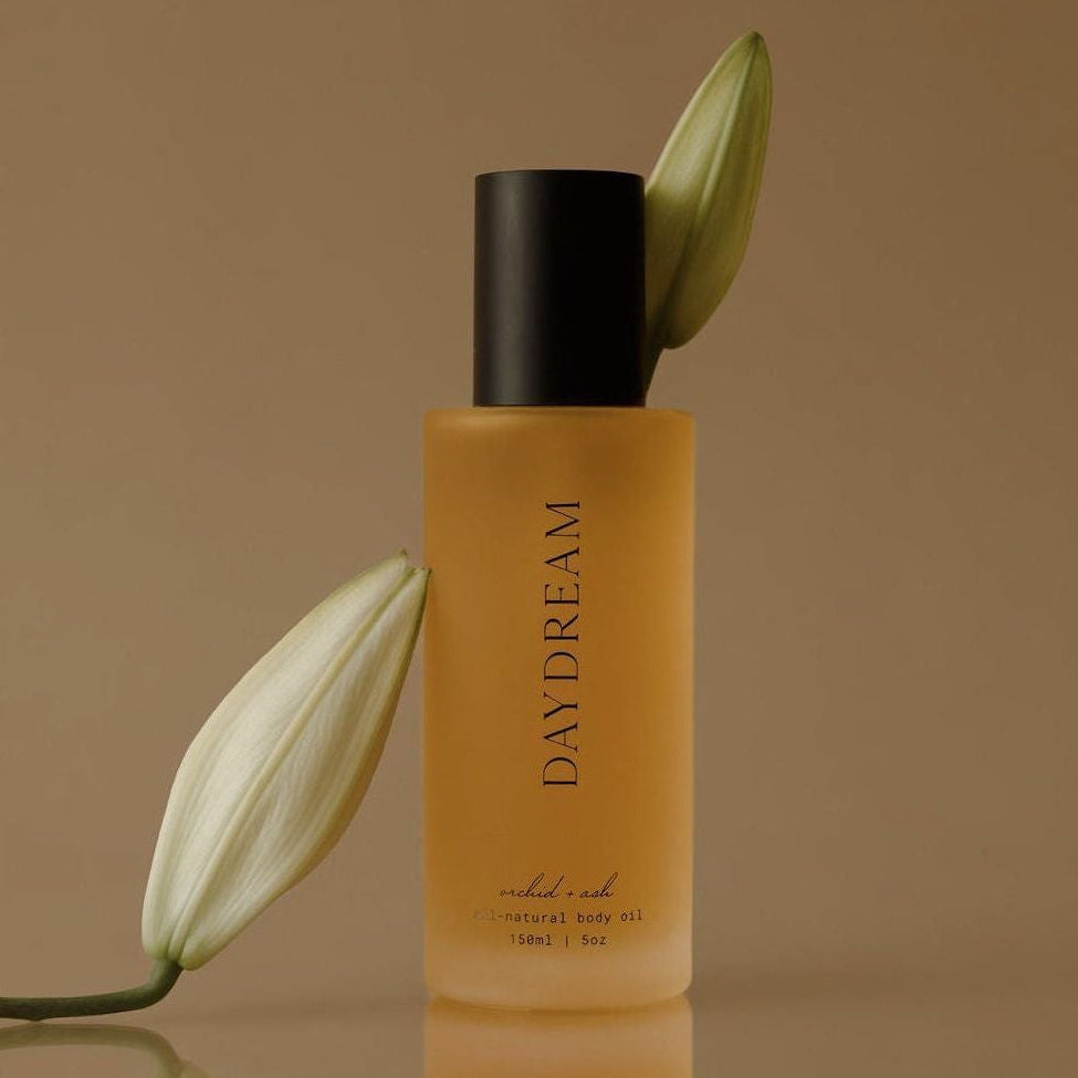 Perfume bottle labeled 'Day Dream' with white flowers on a brown background