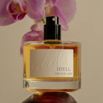 IDYLL Orchid & Ash perfume bottle with pink orchids in the background