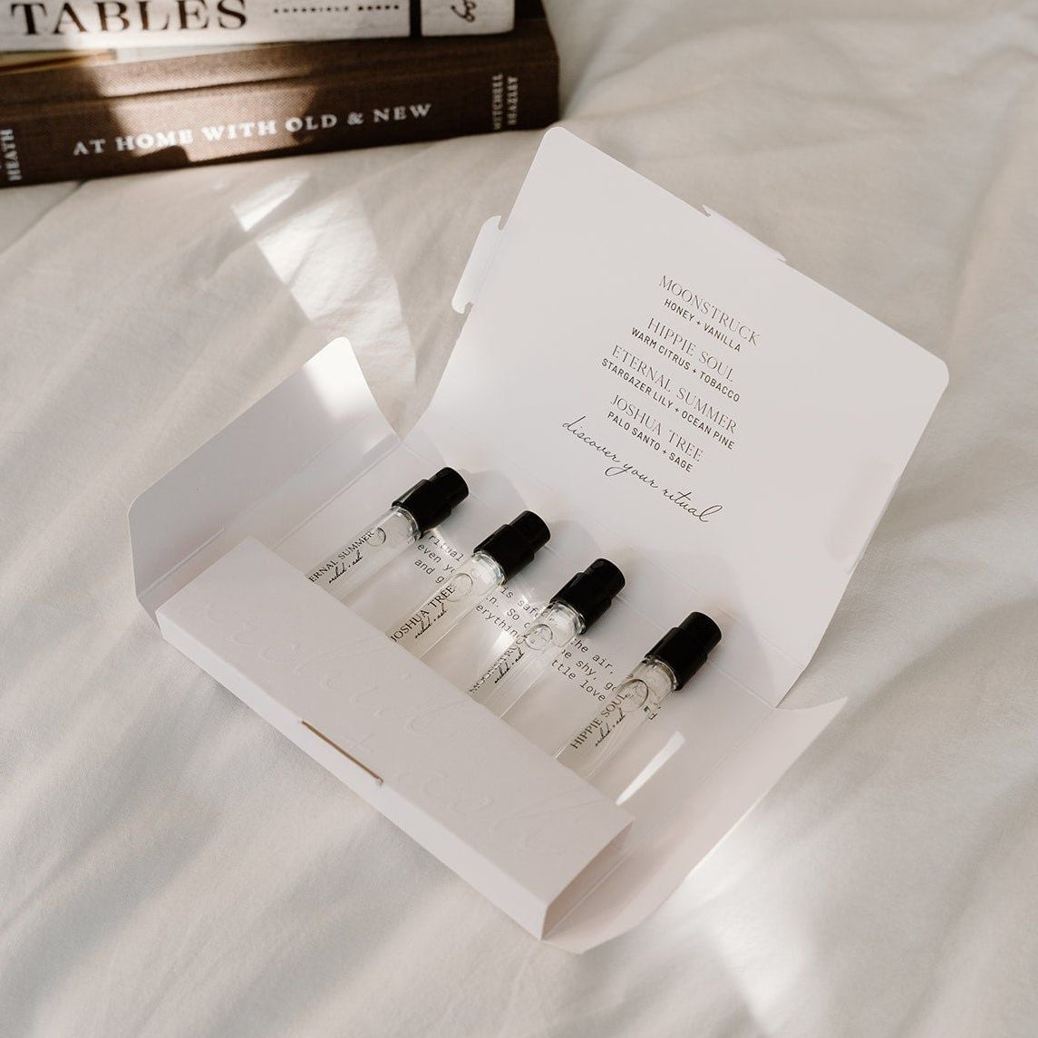 Set of small bottles in a box on a textured surface with a book in the background