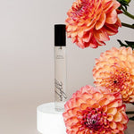 Perfume bottle with pink flowers on a light background