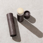 Three cosmetic products on a textured surface with 'BUT. FIRST' branding.