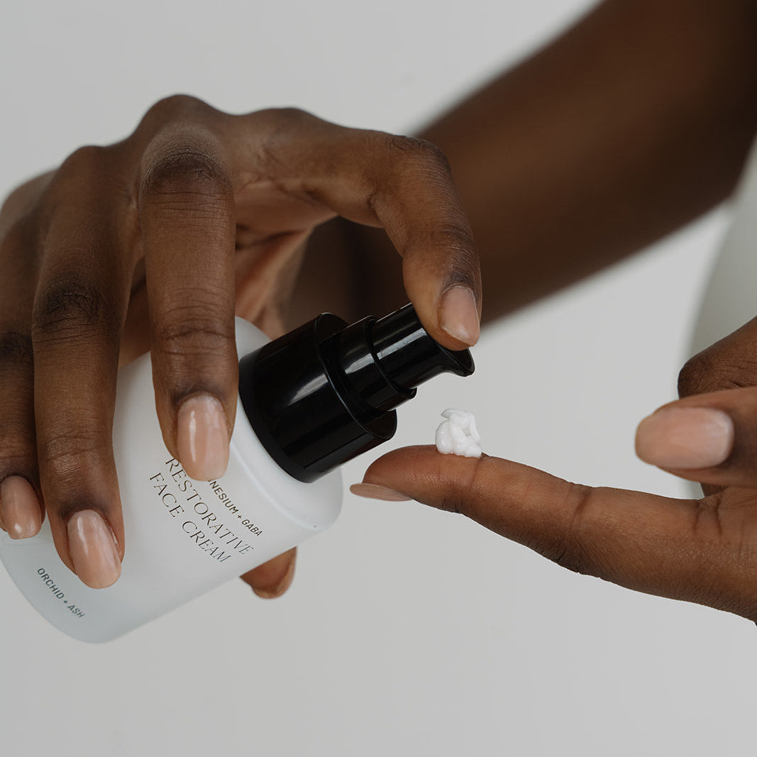 Person applying skincare product to their hand with a dropper bottle.