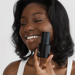 Woman holding a black cosmetic bottle against a white background