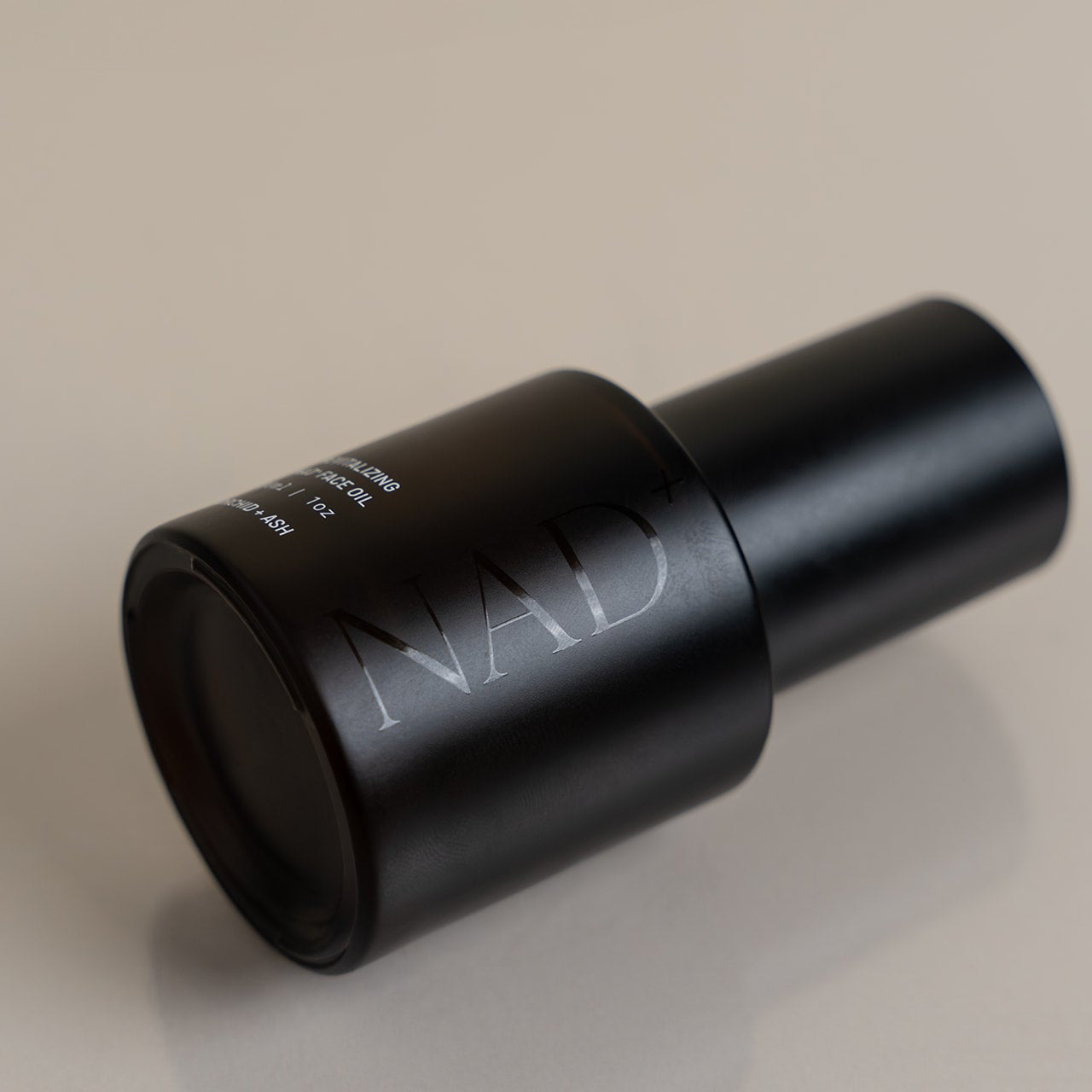 Black cylindrical object with 'NAD' branding on a beige background