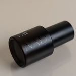 Black cylindrical object with 'NAD' branding on a beige background