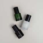Three skincare bottles on a neutral background