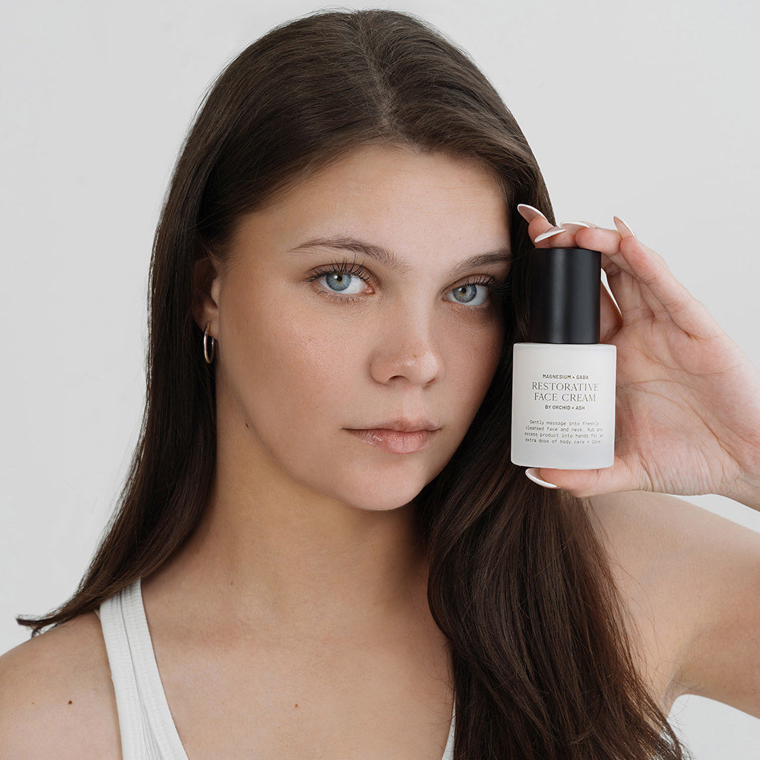 Woman holding a skincare product against a plain background