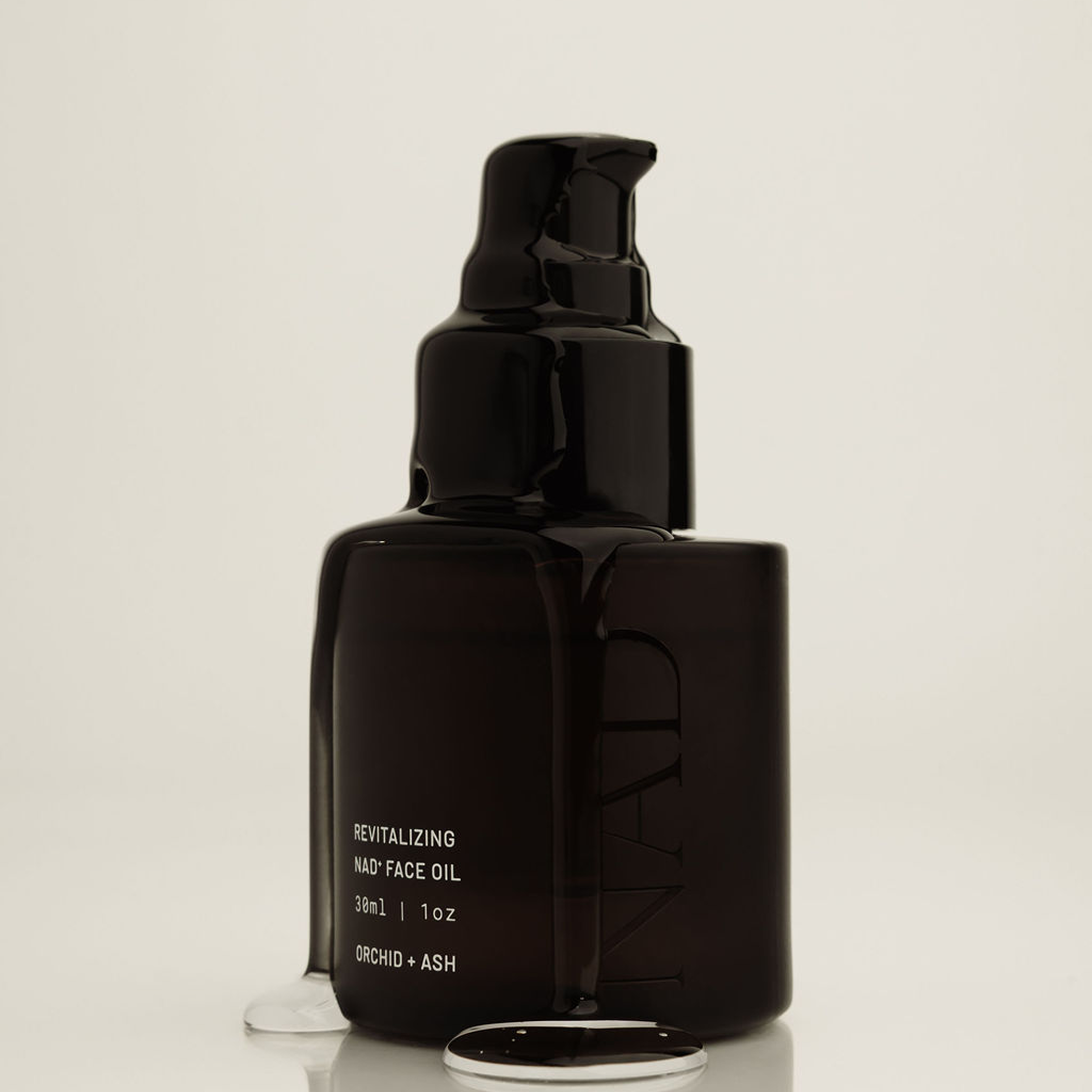 Black facial oil bottle with pump on a light beige background